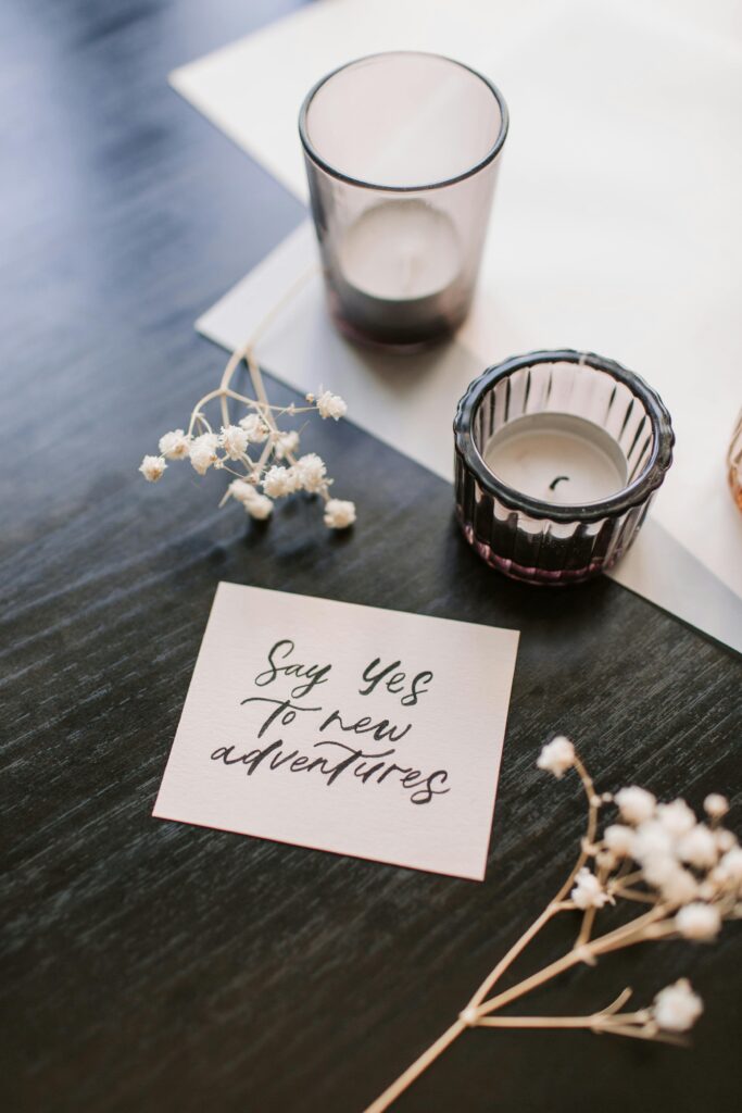 A motivational note with candles and flowers arranged on a dark wooden surface.